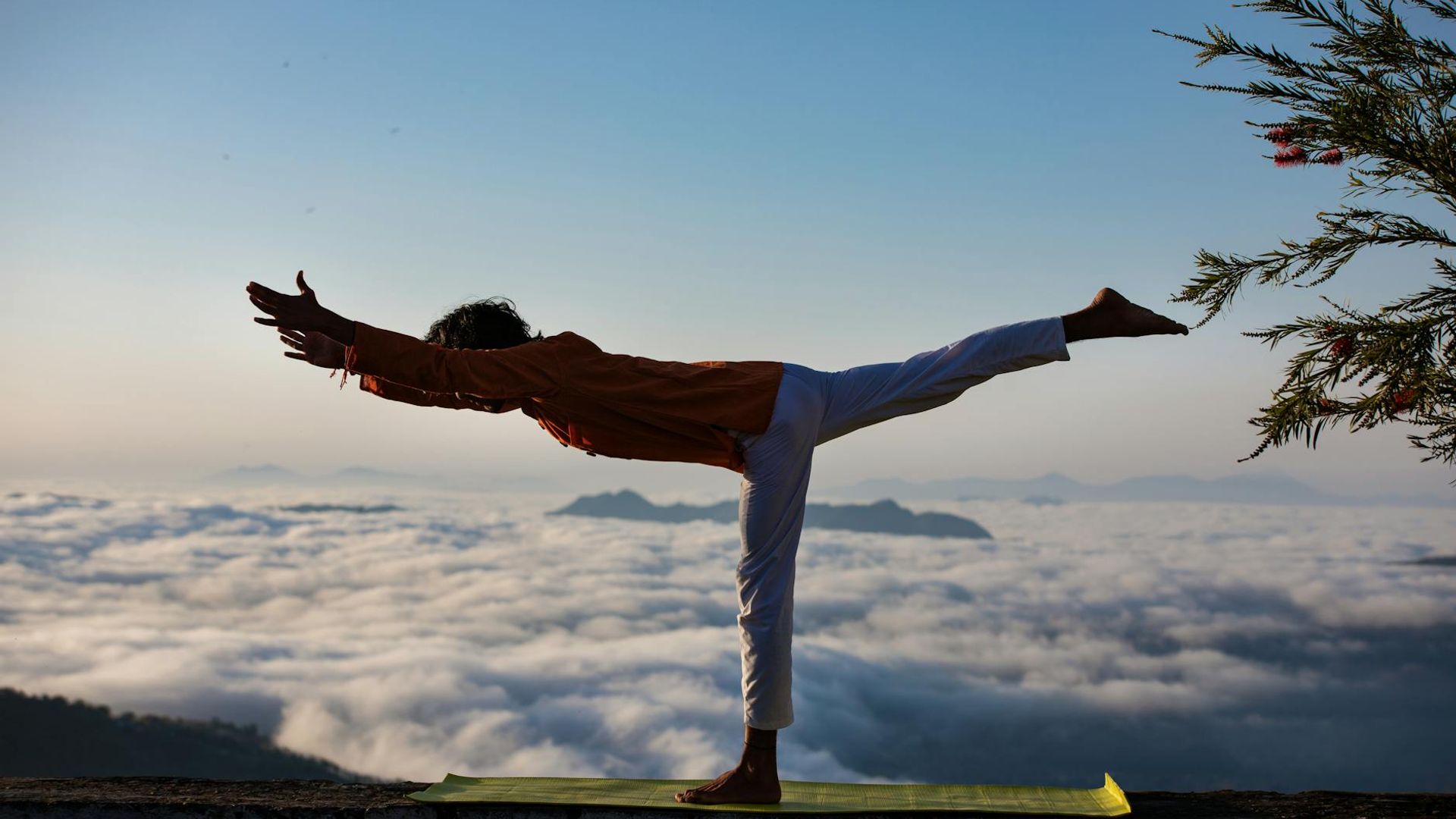 Silhouette of a person in a balanced yoga pose at sunrise.